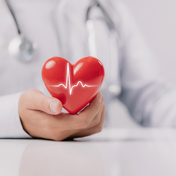 The doctor is holding and showing a red heart with life graph on white background.